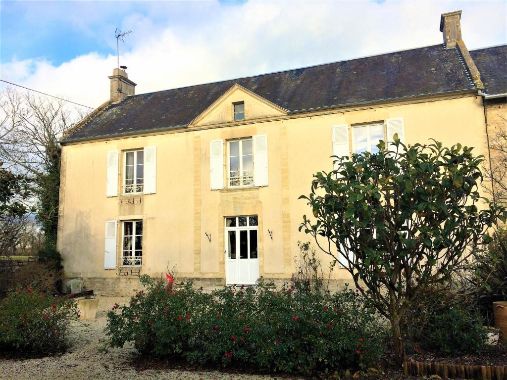 a large yellow house with a roof at Les chambres d'Omaha Beach Etablissement avec deux chambres d'hôtes, petit-déjeuner compris fait-maison et produits locaux in Vierville-sur-Mer