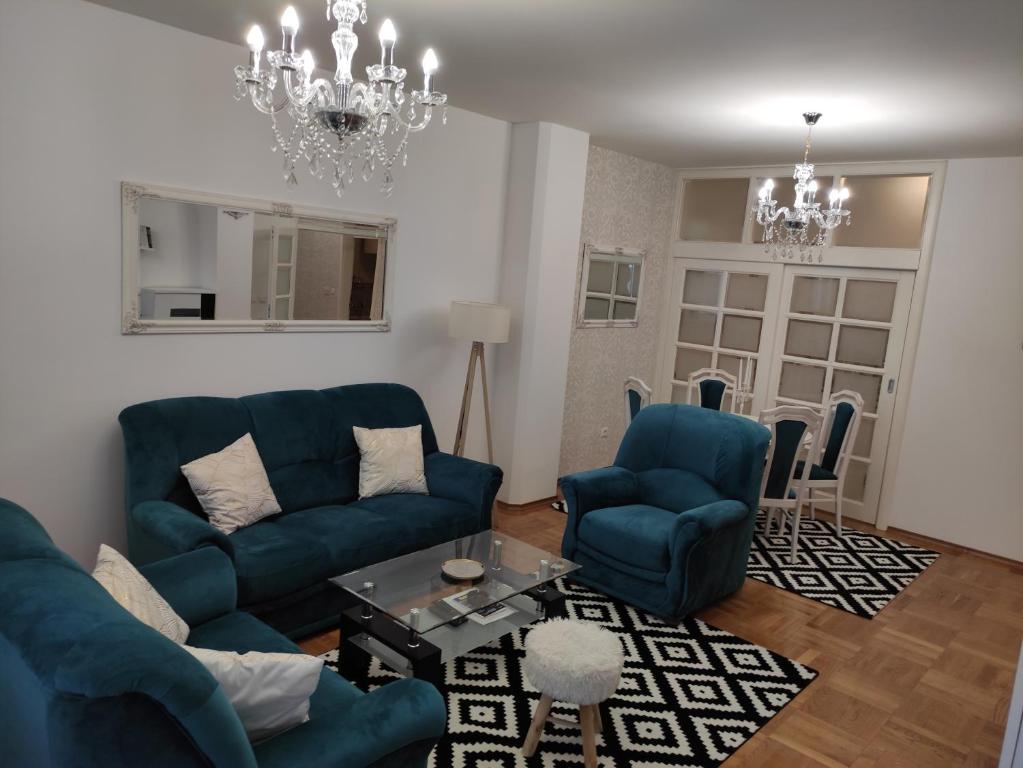 ein Wohnzimmer mit blauen Möbeln und einem Kronleuchter in der Unterkunft Apartment Dajak Centar in Banja Luka