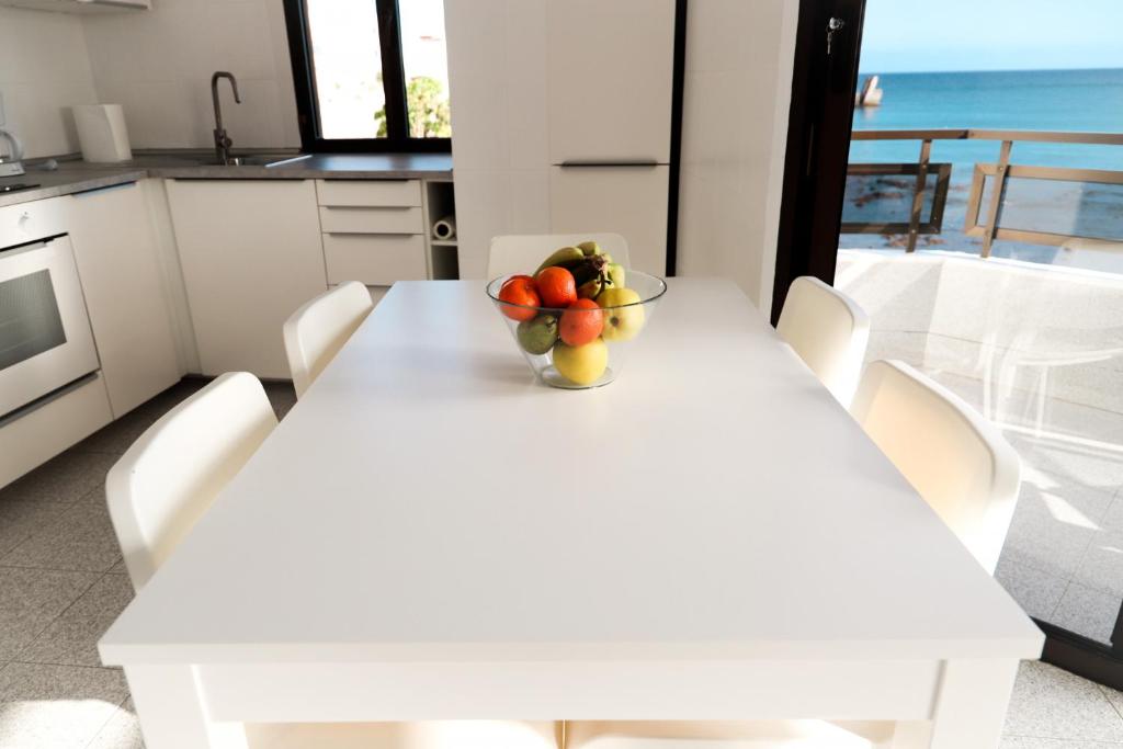 a white table with a bowl of fruit on it at Arinaga Colors, tu casa en la playa in Arinaga