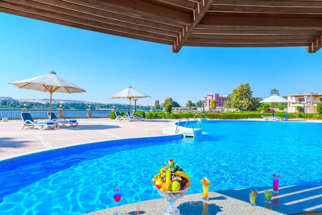 a swimming pool with a bowl of fruit on a table next to it at Tolip Aswan Hotel in Aswan