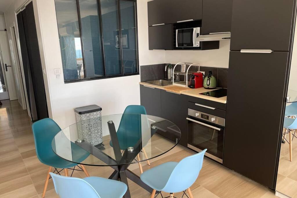 a kitchen with a glass table and blue chairs at Vue mer port de garavan in Menton