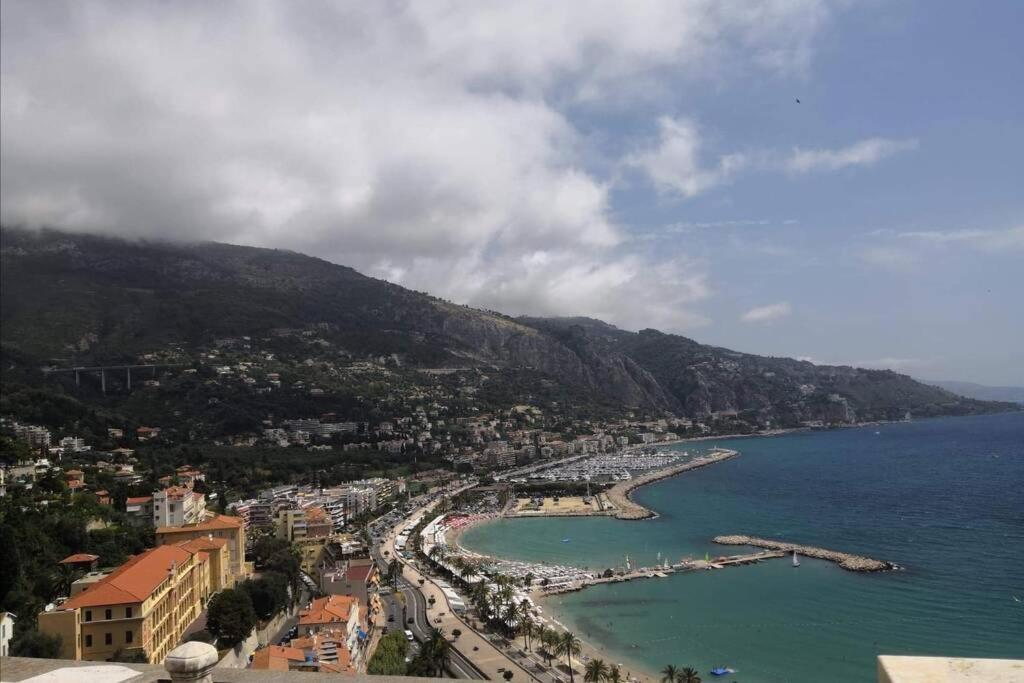 a view of a beach with a city and the ocean at Vue mer port de garavan in Menton