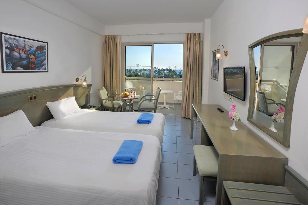 a hotel room with two beds and a kitchen with a view at Nissiana Hotel & Bungalows in Ayia Napa