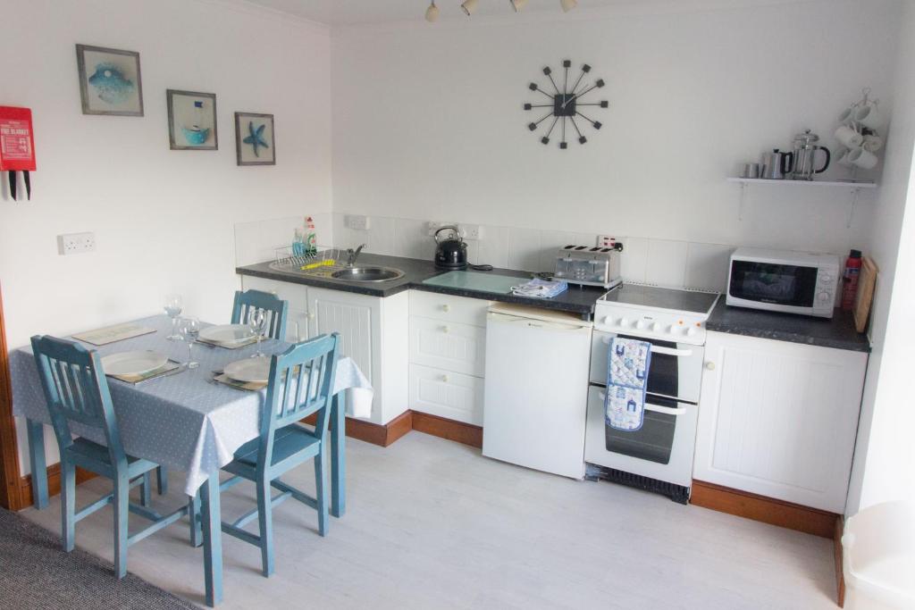 a kitchen with a table and a stove and a microwave at Utopia Apartments in Perranporth