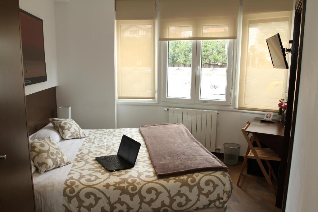 Un dormitorio con una cama con una computadora portátil encima. en Pensión Grosen, en San Sebastián