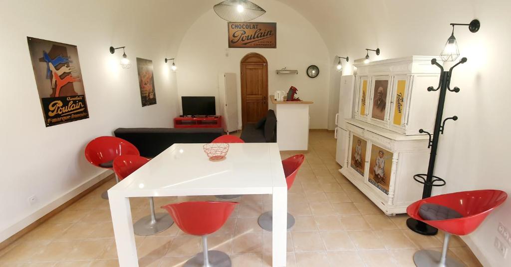 sala de estar con mesa blanca y sillas rojas en Appartement "La Chocolaterie" en Centre-Ville linge inclus en Blois