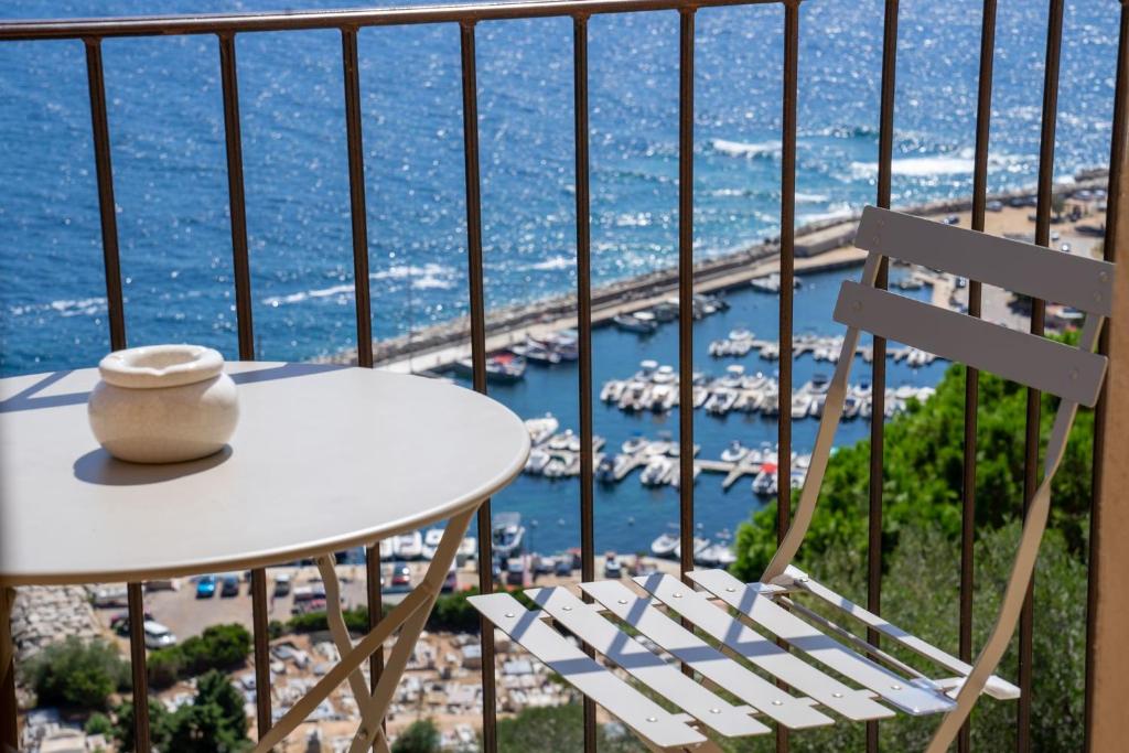 een tafel en een stoel op een balkon met een haven bij Cargèse, appartement de charme surplombant le port in Cargèse