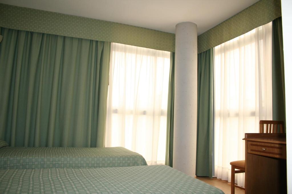 1 dormitorio con 1 cama y ventanas con cortinas verdes en Hotel Austria 76 en Puerto de Sagunto