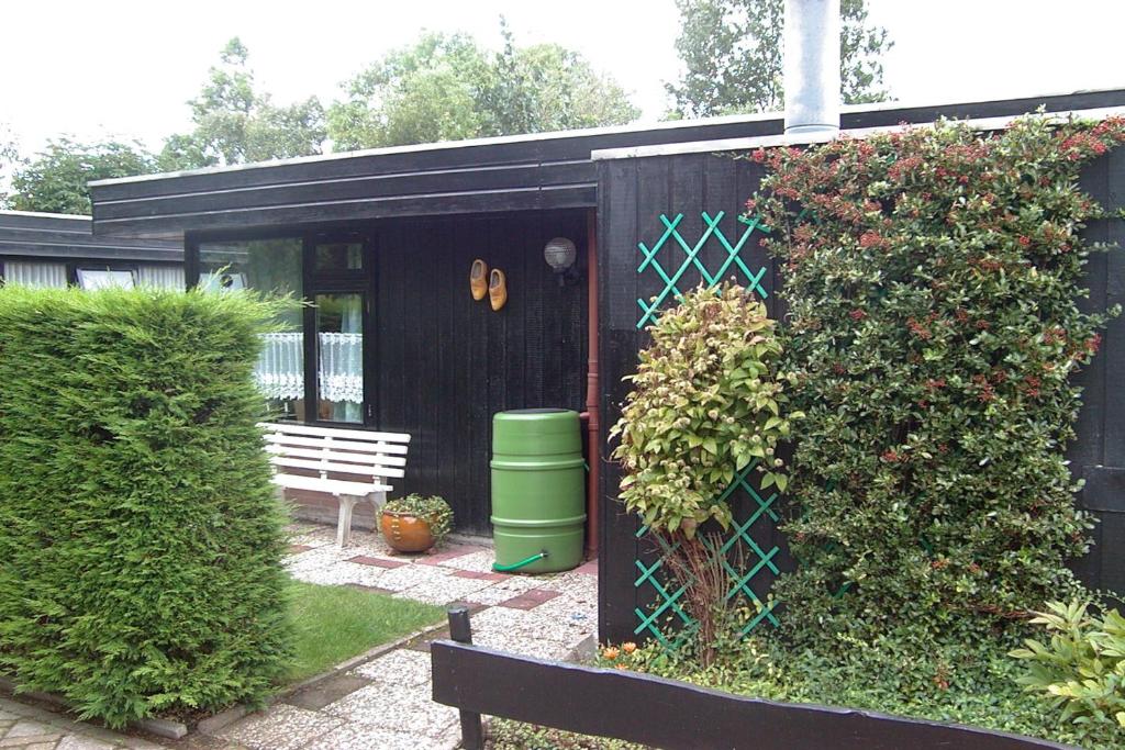 um barracão preto com um banco num jardim em Vakantiehuis Friedeburg em Warmenhuizen