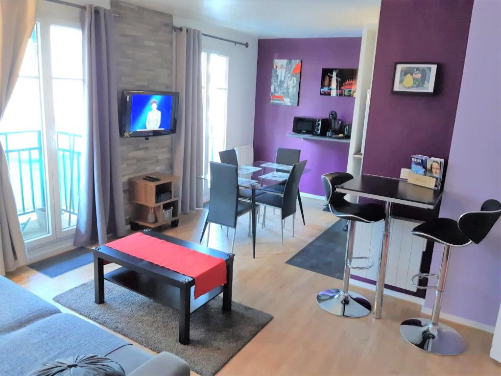 Briget Apartment في شيسي: غرفة معيشة مع جدران أرجوانية وطاولة وكراسي
