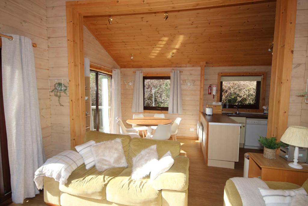 a living room with a couch and a kitchen at Hartland Hideaway Lodge in Woolfardisworthy