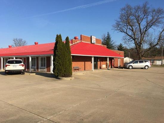 een gebouw met een rood dak en twee auto's geparkeerd op een parkeerplaats bij Foster Inn Monticello in Monticello