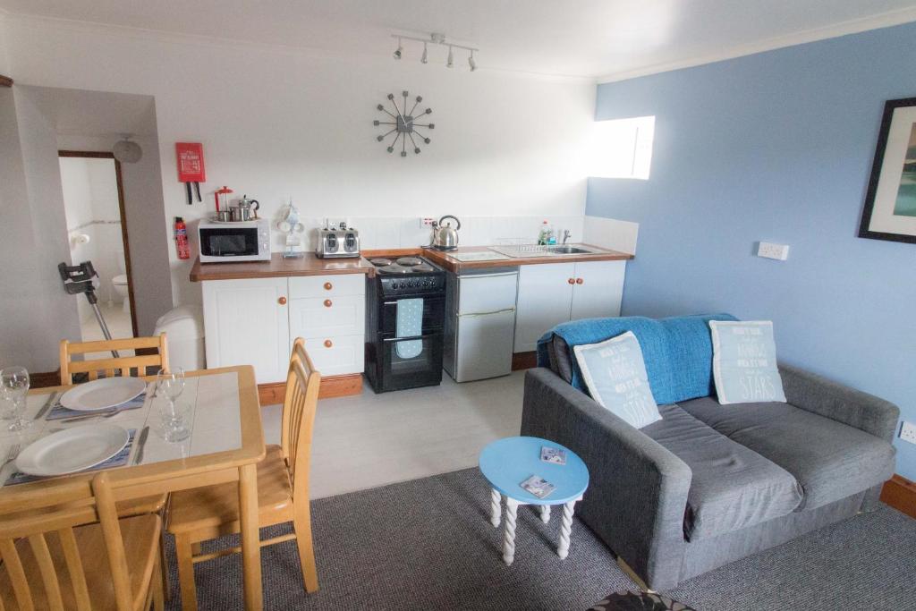 a living room with a couch and a table and a kitchen at Utopia Apartments in Perranporth