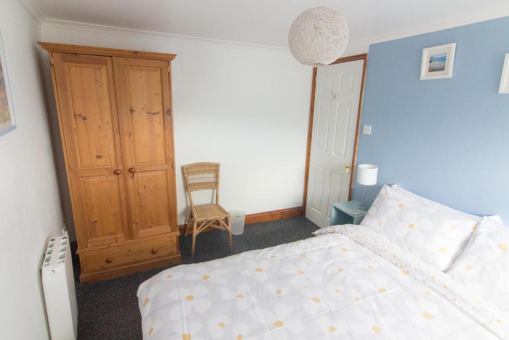 a bedroom with a bed and a wooden cabinet at Utopia Apartments in Perranporth