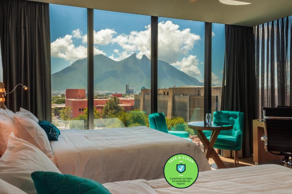 a hotel room with two beds and a view of a mountain at Hotel Kavia Monterrey in Monterrey