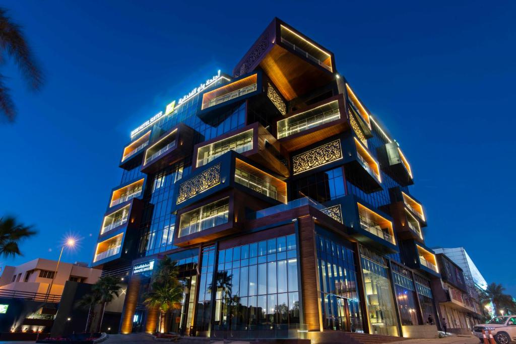 un edificio alto con ventanas de cristal por la noche en WAW Hotel Suites King Abdullah District, en Riad