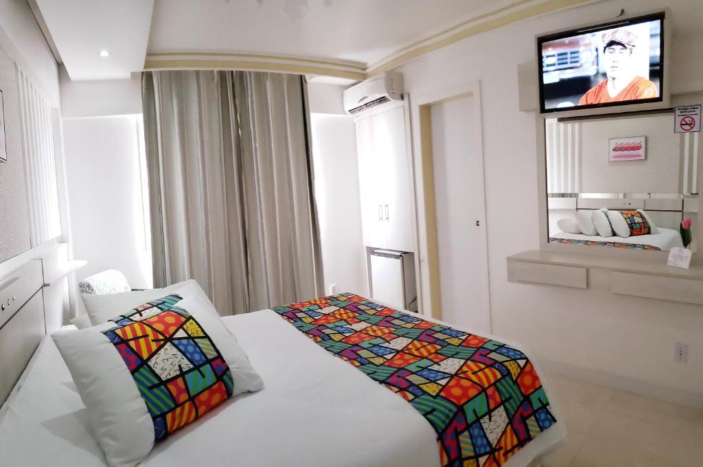 a hotel room with a bed with a colorful quilt on it at Hotel Rediadri - Capão da Canoa in Capão da Canoa