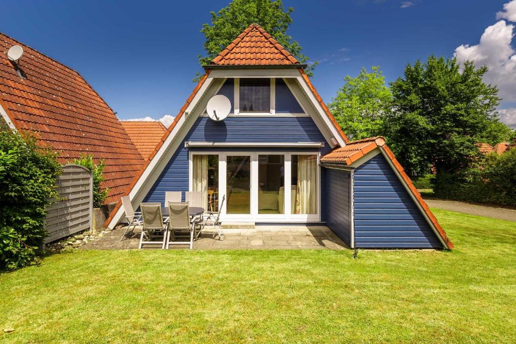 ein kleines blaues Haus mit Stühlen im Hof in der Unterkunft Ferienwohnpark Immenstaad am Bodensee Nurdachhaus Typ 8 NDT 014 in Immenstaad am Bodensee