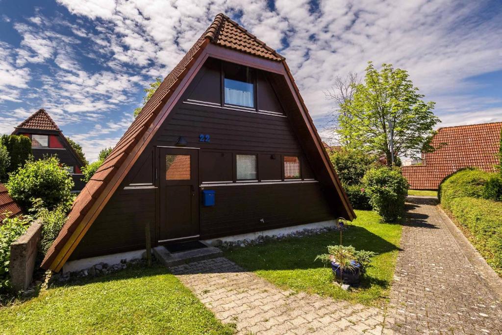 ein kleines Haus mit einem Gamer-Dach auf einem Hof in der Unterkunft Ferienwohnpark Immenstaad am Bodensee Nurdachhaus Typ 8 NDT 022 in Immenstaad am Bodensee