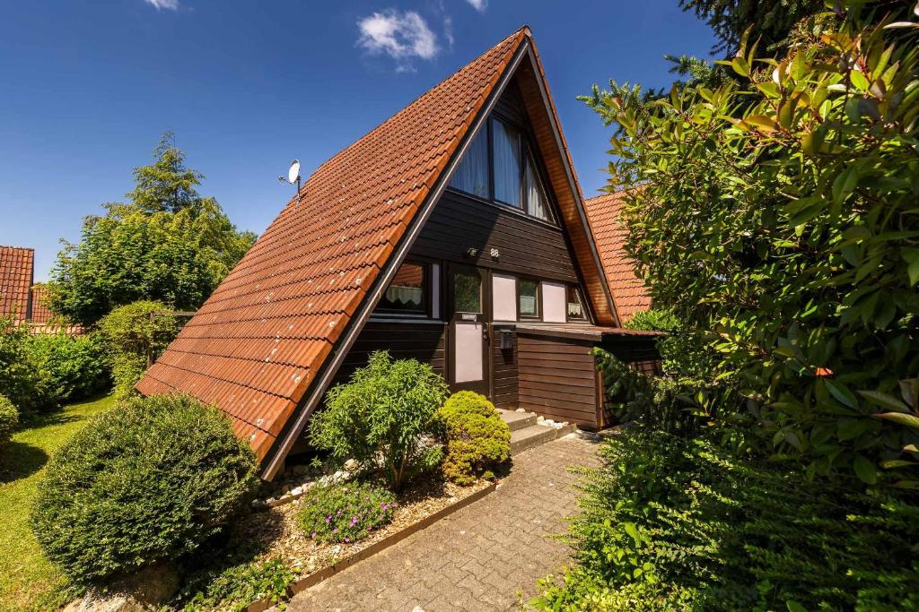 une maison avec un toit orange et un jardin dans l'établissement Ferienwohnpark Immenstaad am Bodensee Nurdachhaus Typ 8 NDW 088, à Immenstaad am Bodensee