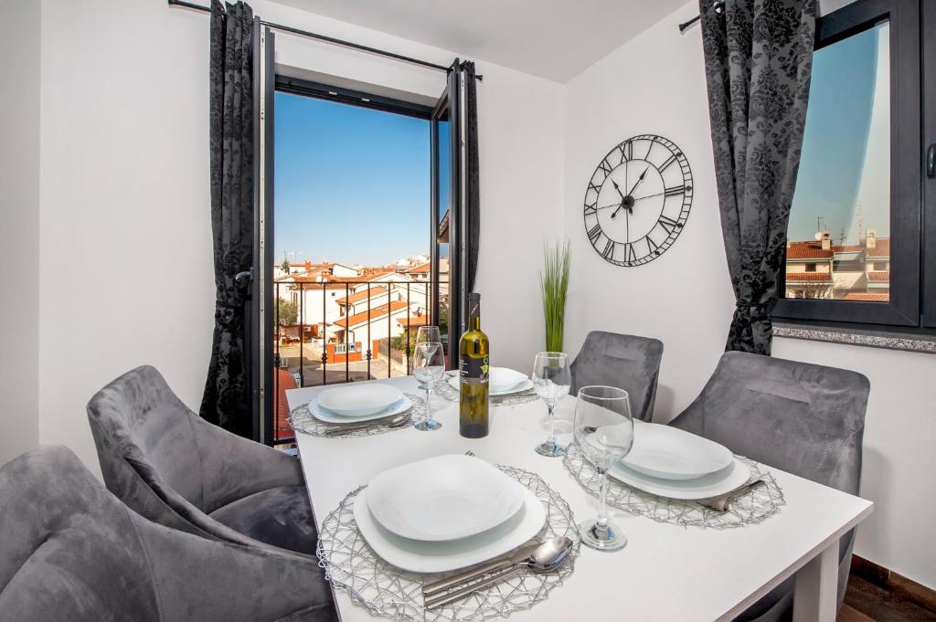 a dining room with a table and chairs and a clock at Deluxe Apartments A&A in Rovinj