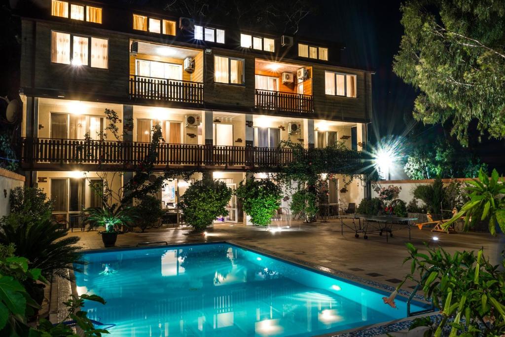 a hotel with a swimming pool in front of a building at Guest house Skazka in Gagra