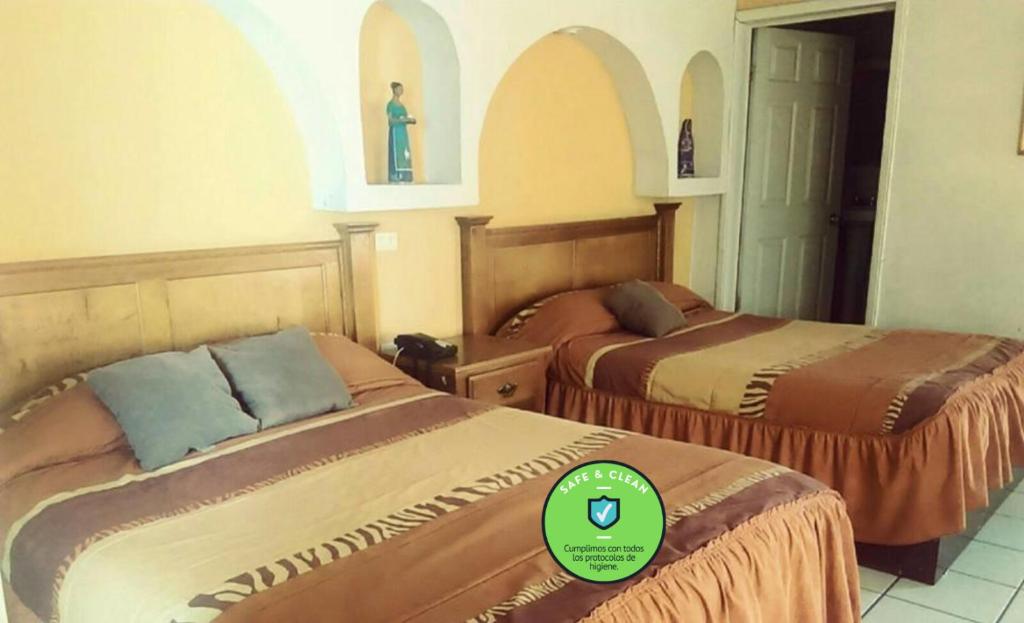 a hotel room with two beds with a green sticker on them at HOTEL BAEZA in Delicias