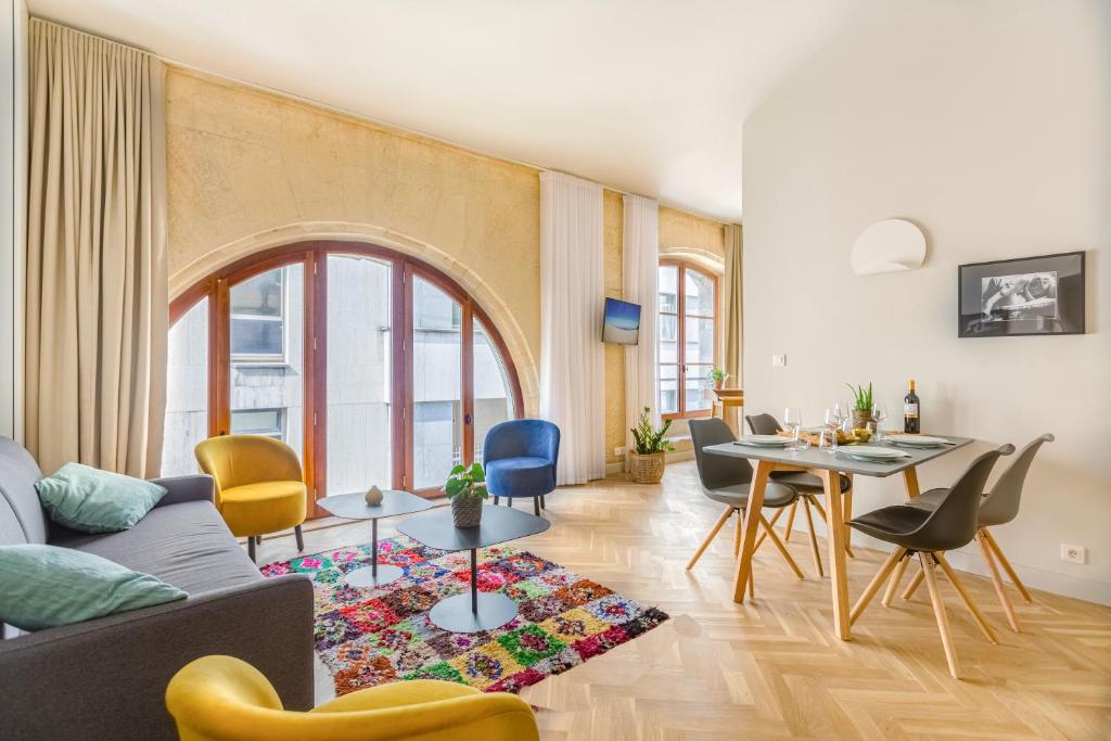 een woonkamer met een bank en een tafel en stoelen bij Les Suites de Saint Amand in Bordeaux