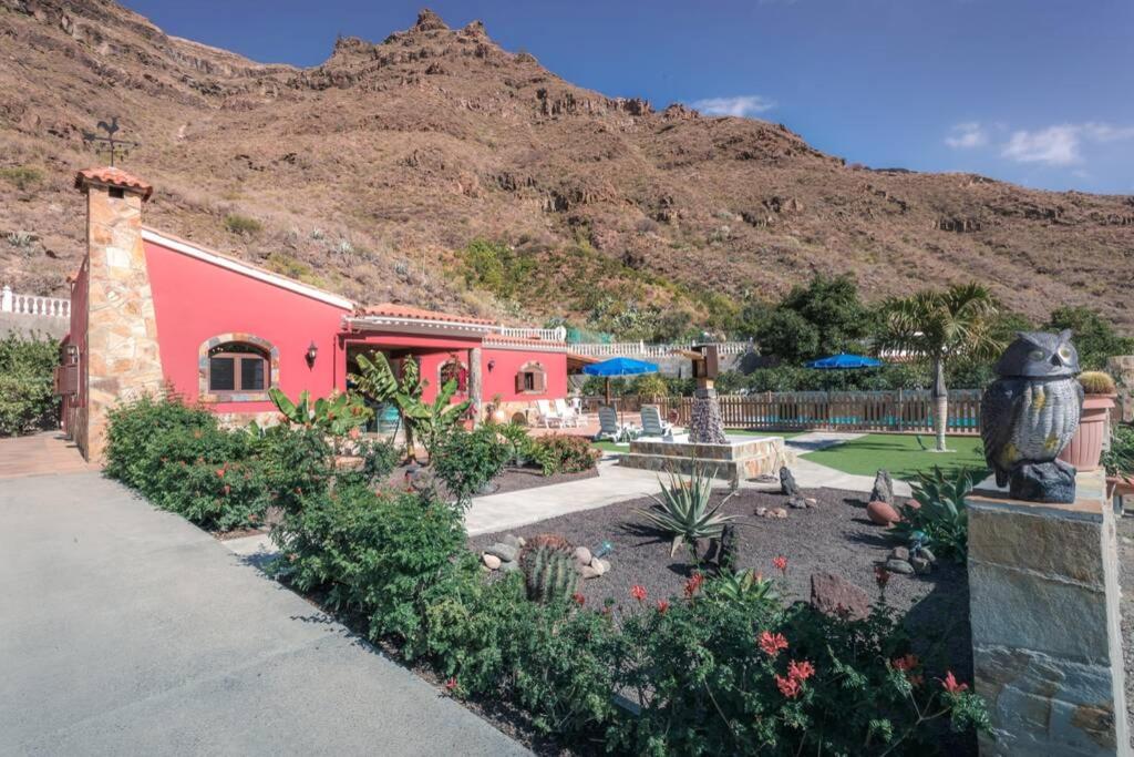 un bâtiment rose avec une montagne en arrière-plan dans l'établissement Vivienda Vacacional La Finca, à Los Palmitos