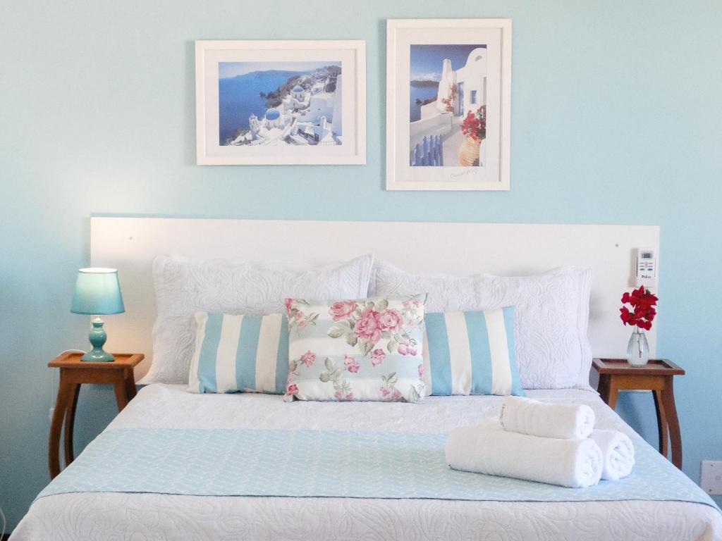 ein Schlafzimmer mit einem weißen Bett mit drei Bildern an der Wand in der Unterkunft Viva Buzios in Búzios