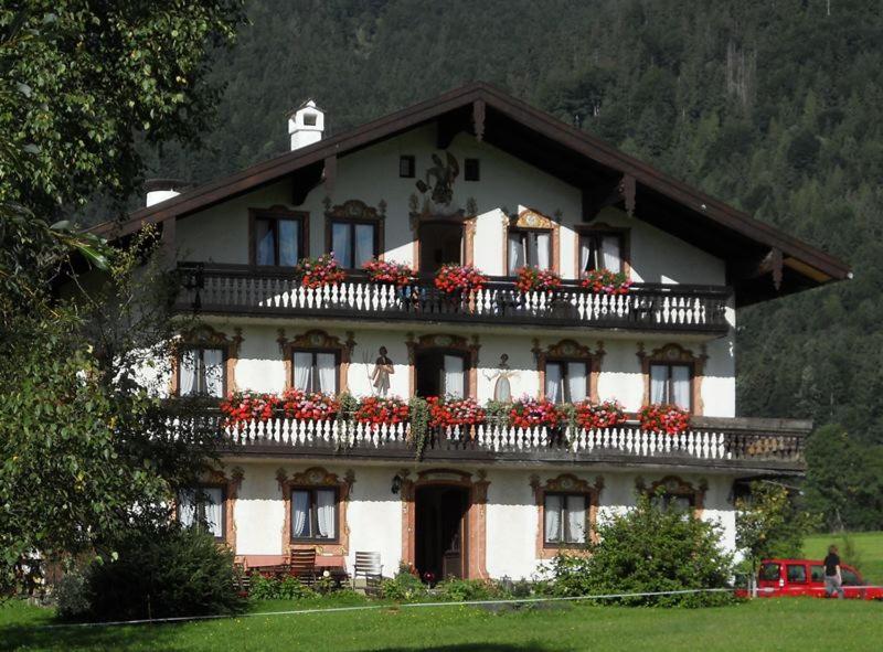a large house with red flowers on the balcony at Schusterbauer-Hof in Schleching