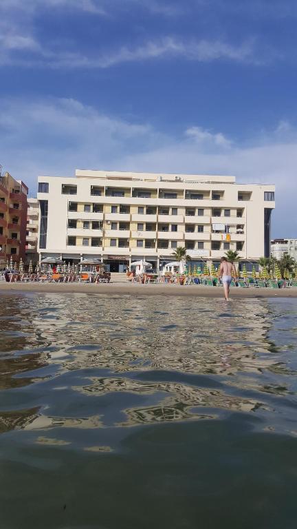 a woman standing in the water in front of a building at Joel Residence in Durrës