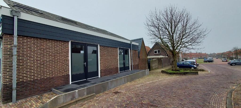un bâtiment en briques avec une voiture garée dans une rue dans l'établissement t Gasthuys, à Den Oever