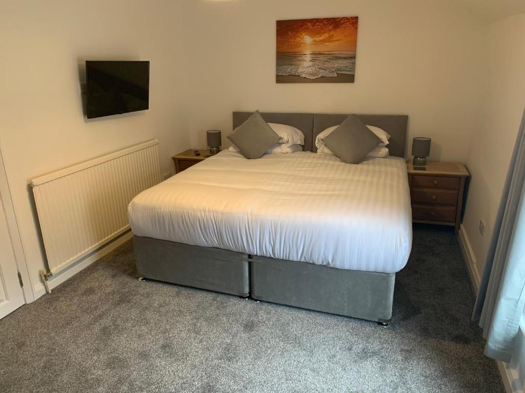 a bedroom with a bed and a tv on the wall at Rooms at the Inn in Retford