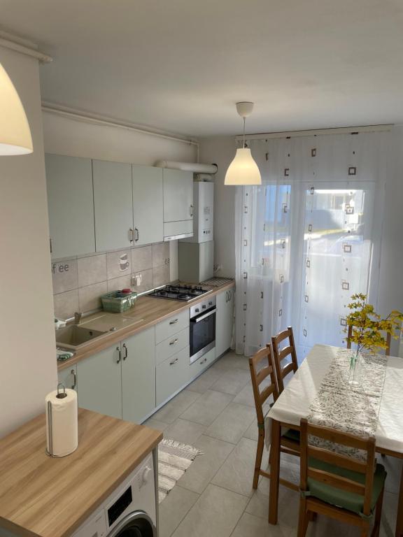 a kitchen with white cabinets and a table with chairs at Roxi's Apartment in Sibiu
