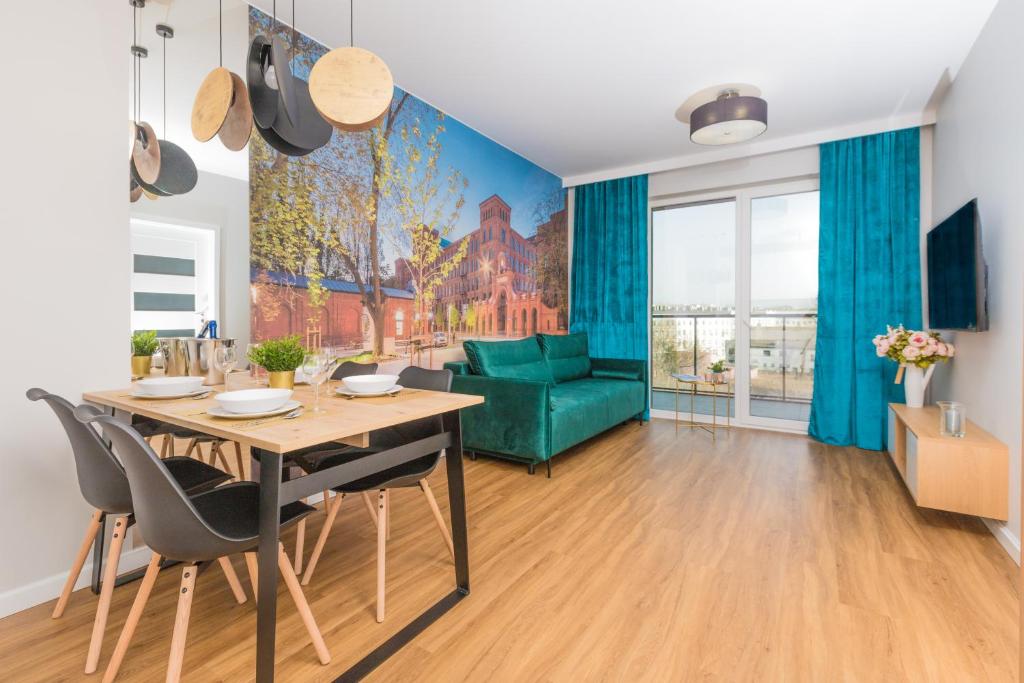 een woonkamer met een tafel en een groene bank bij Royal Manu Apartment NETFLIX in Łódź