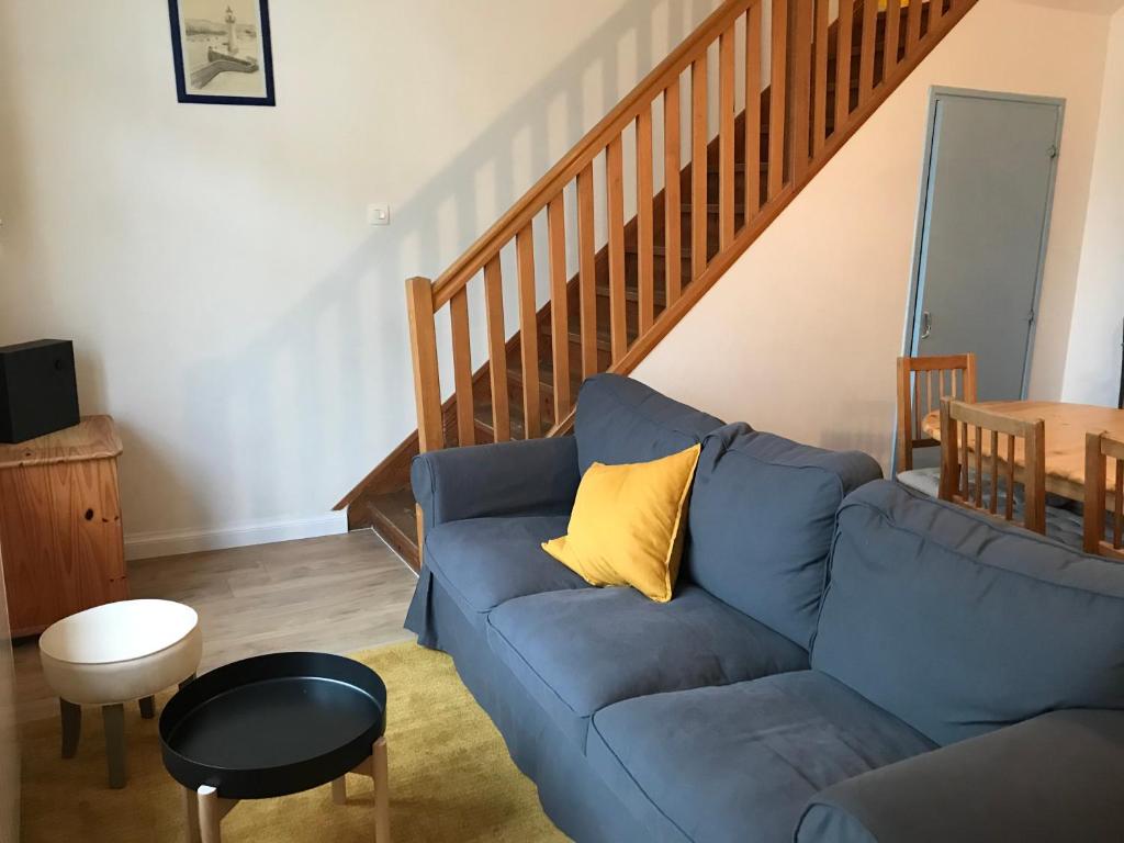 a living room with a blue couch with a yellow pillow at Jolie maison à Wissant proche de la plage in Wissant