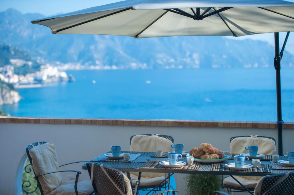 a table with food and an umbrella on a balcony at APPARTAMENTO LE MIRAGE in Conca dei Marini