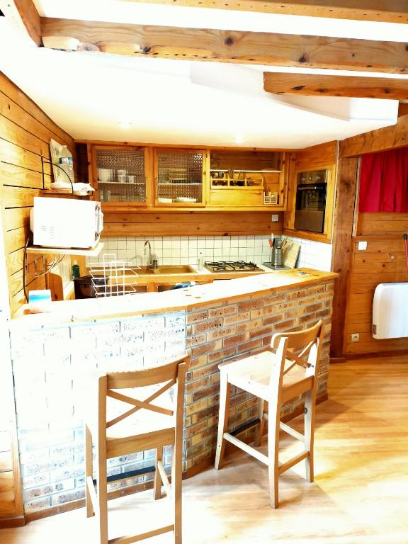 - une cuisine avec 2 chaises et un comptoir dans l'établissement Duplex de 65 m² à l'esprit chalet, à La Bourboule