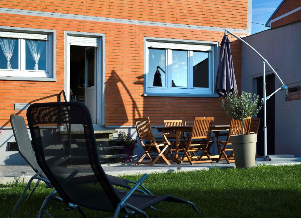 un patio con sillas, una mesa y una sombrilla en La Maison Orange, en Bully-les-Mines