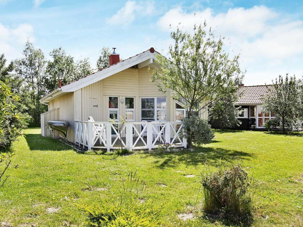 uma pequena casa com uma cerca branca e um quintal em 4 person holiday home in Otterndorf em Otterndorf
