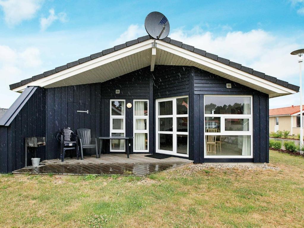 una casa negra con techo inclinado y patio en 6 person holiday home in GROEMITZ, en Grömitz