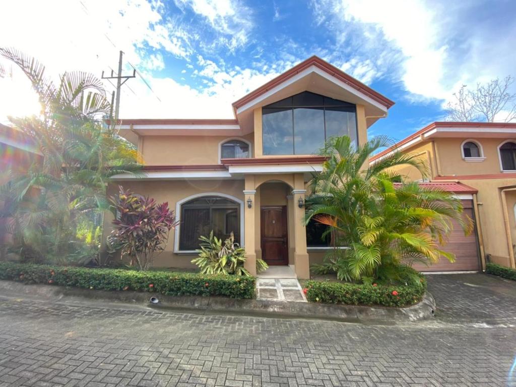 a house with a lot of plants in front of it at Family oriented house just steps to the beach in Jacó