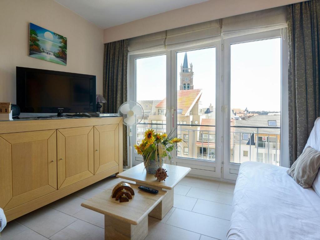 een woonkamer met een tv en een groot raam bij Simplistic Apartment in Blankenberghe near Belgium Pier in Blankenberge