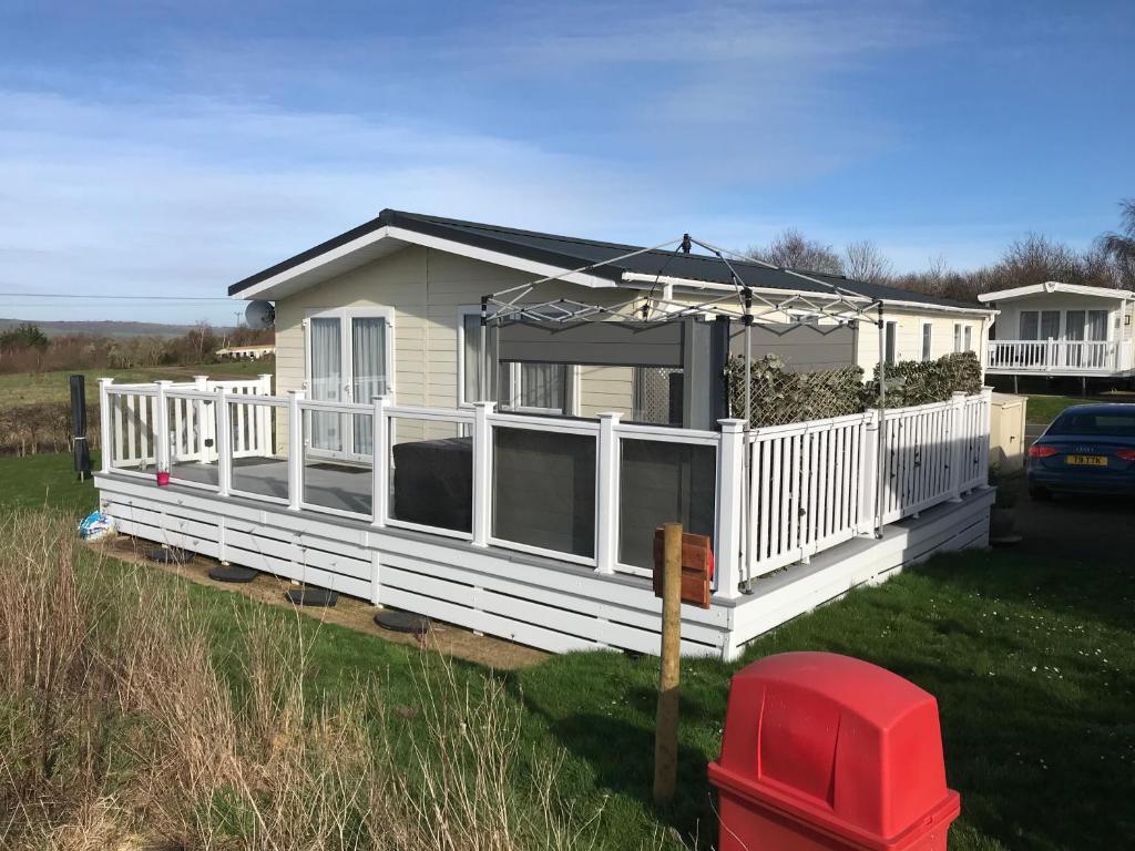 2 Bedroom Luxury Lodge, OG30, Shanklin, Isle of Wight في شانكلين: منزل متنقل أبيض مع شرفة ومظلة