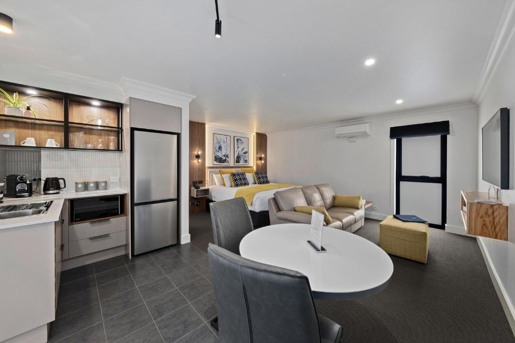 a kitchen and a living room with a table in a room at Bluegum Dubbo Motel in Dubbo