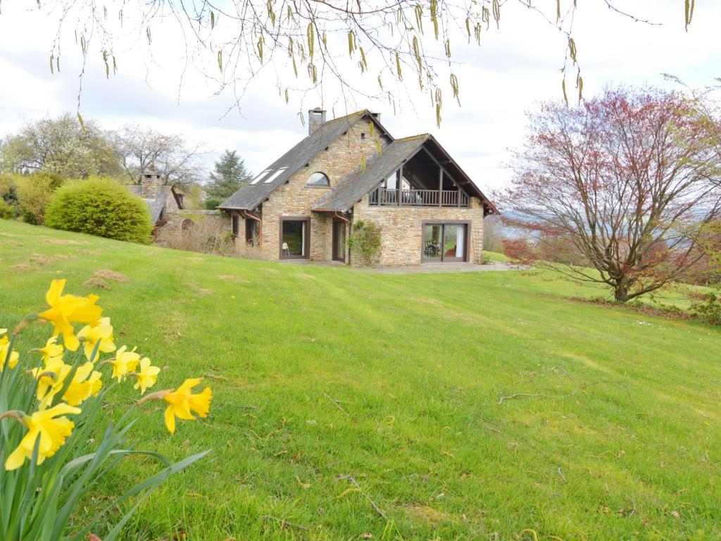 a stone house on a grassy field with flowers at Villa with 5 bedrooms and 4 bathrooms in Lierneux