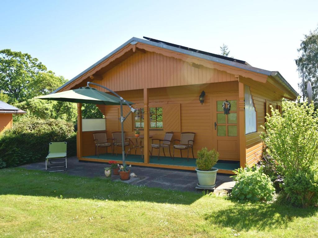 a small cabin with chairs and an umbrella at Serene Holiday Home in K gsdorf with Sea View in Kägsdorf