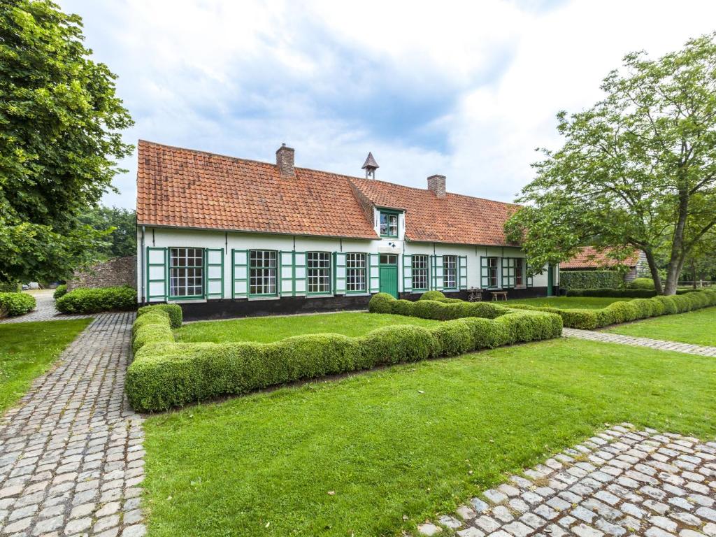 貝爾內姆的住宿－Beautiful farmhouse in Beernem with big garden，一座带红色屋顶和绿色庭院的古老房子