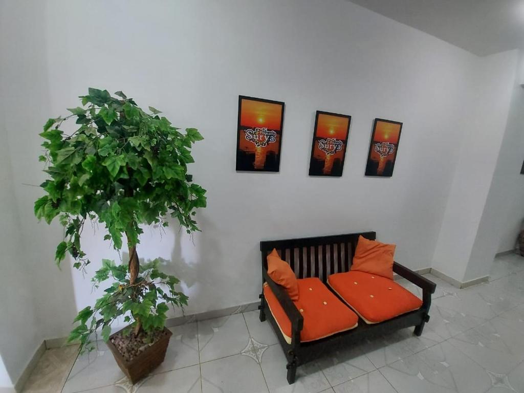 una panchina con cuscini arancioni accanto a un muro con quattro dipinti di Pousada Surya a Pôrto Velho
